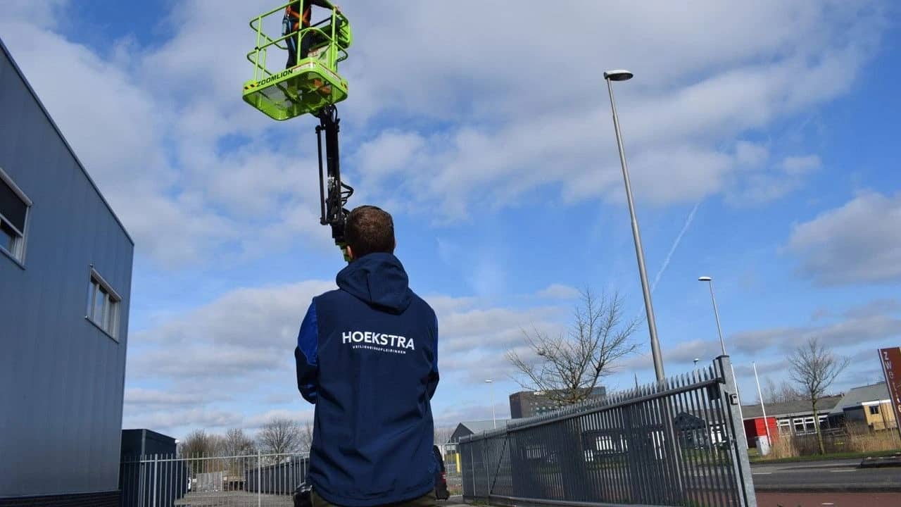 Cursist van Hoekstra Veiligheidsopleidingen kijkt toe bij een hoogwerker in werkstand
